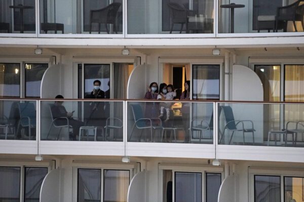 Passengers from the cruise ship "World Dream" docked at Kai Tak cruise terminal, wave to family members on shore in Hong Kong, Saturday, Feb. 8, 2020. The cruise ship "World Dream" with approximately 1,800 passengers remained quarantined in Hong Kong’s Victoria Harbour on Saturday. Several passengers from mainland China on a previous World Dream cruise were found to have the new coronavirus on returning home. (AP Photo/Kin Cheung)