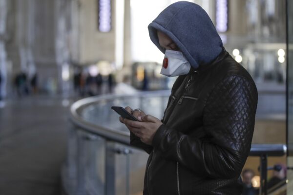 A man wearing a sanitary mask holds a smartphone at the Centrale main railway station in Milan, Italy, Monday, Feb. 24, 2020. Italy has been scrambling to check the spread of Europe’s first major outbreak of the new viral disease amid rapidly rising numbers of infections and a third death, calling off the popular Venice Carnival, scrapping major league soccer matches in the stricken area and shuttering theaters, including Milan’s legendary La Scala. (AP Photo/Luca Bruno)