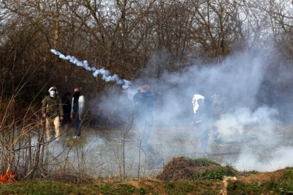 A migrants throws a tear gas at Greek police during clashes at the Turkish-Greek border near the Pazarkule border gate in Edirne, Turkey on Monday, March 2, 2020.Thousands of migrants and refugees massed at Turkey’s western frontier, trying to enter Greece by land and sea after Turkey said its borders were open to those hoping to head to Europe. (AP Photo/Darko Bandic)