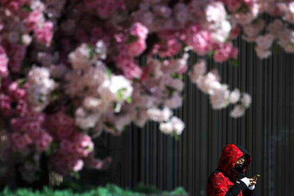 A masked woman browses her smartphone as she walks by the Wangfujing shopping district in Beijing, Tuesday, March 10, 2020. For most people, the new coronavirus causes only mild or moderate symptoms, such as fever and cough. For some, especially older adults and people with existing health problems, it can cause more severe illness, including pneumonia. (AP Photo/Andy Wong)