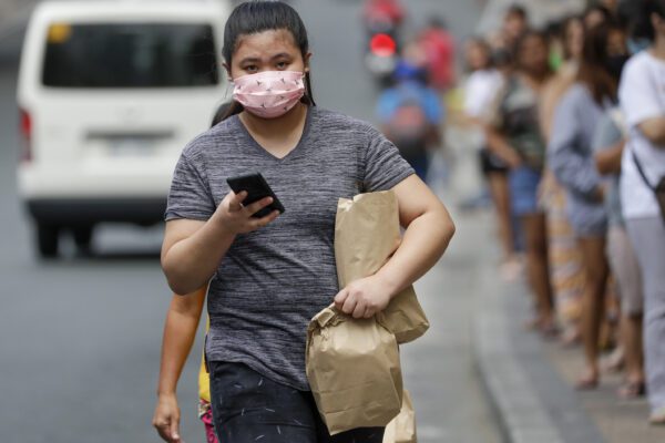 A woman wears a protective masks outside a supermarket as a precautionary measure against the spread of the coronavirus in Metro Manila, Philippines Tuesday, March 17, 2020. For most people, the new coronavirus causes only mild or moderate symptoms. For some, it can cause more severe illness, especially in older adults and people with existing health problems. (AP Photo/Aaron Favila)