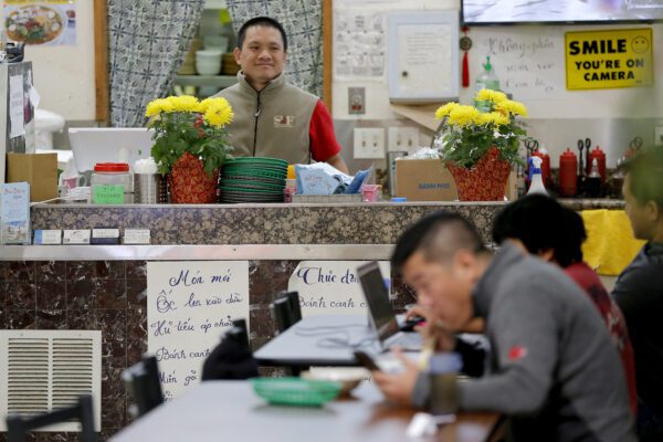 In this Feb. 13, 2020, photo, restaurant owner Phong Nguy watches from his counter as customers eat lunch in the food court at the Mekong Plaza in the Asian district, in Mesa, Ariz. Arizona’s freshly crowned Asian District was deep into organizing its night market when news broke that a case of the illness known as COVID-19 was confirmed at nearby Arizona State University. Xenophobic comments on social media and phone calls started almost immediately, according to Arizona Asian Chamber of Commerce CEO Vicente Reid. (AP Photo/Matt York)