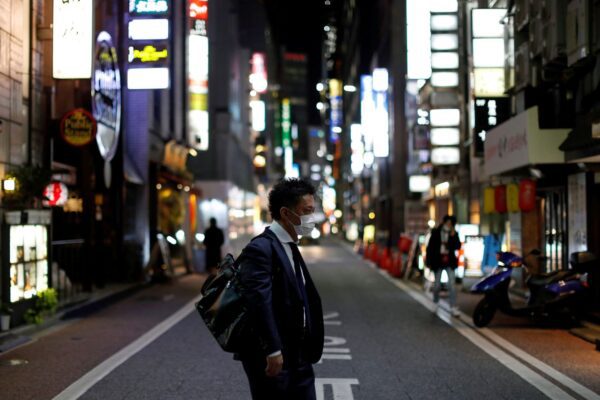 A man wearing a protective face mask, following an outbreak of the coronavirus disease (COVID-19), walks at Ginza shopping and amusement district in Tokyo, Japan April 2, 2020.    REUTERS/Issei Kato