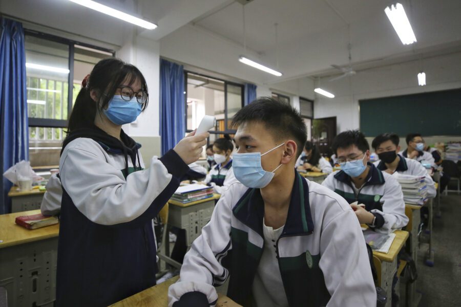 A female student wearing a protective face mask to help curb the spread of the new coronavirus checks temperature of her classmates at a high school in Wuhan in central China’s Hubei province, Wednesday, May 6, 2020. Senior students returned to classes on Wednesday in the central Chinese city of Wuhan, the epicenter of the coronavirus pandemic, after no new cases or deaths were reported from the outbreak that had prompted a 76-day quarantine in the city of 11 million. (Chinatopix via AP)