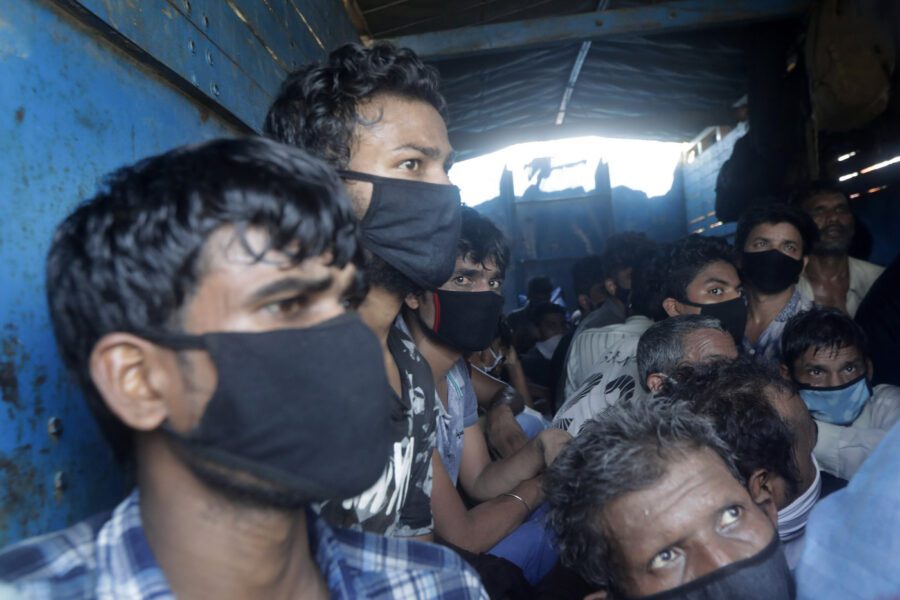 Migrant workers who were traveling in a truck to return to their home state of Uttar Pradesh are detained by police in Mumbai, India, Saturday, May 9, 2020.  Locking down the country’s 1.3 billion people has slowed down the spread of the virus, but has come at the enormous cost of upending lives and millions of lost jobs. (AP Photo/Rajanish Kakade)
