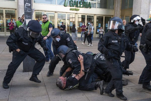 Police officers apprehend a man at a demonstration on Alexanderplatz in Berlin, Germany after several hundred people gathered for an unsanctioned demonstration Saturday May 9, 2020. According to a spokesperson, police officers pointed out to the demonstrators the regulations for containing the coronavirus pandemic. (Christophe Gateau/DPA via AP)