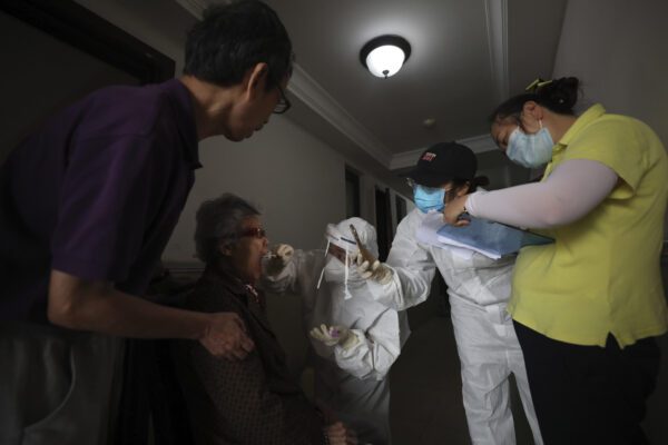 A medical worker takes a swab from a resident for the coronavirus test during home visits in Wuhan the epicenter of China’s coronavirus outbreak in central China’s Hubei province, Thursday, May 14, 2020. Some residential compounds in Wuhan have begun testing inhabitants for the coronavirus as a program to test everyone in the Chinese city of 11 million people in 10 days got underway (Chinatopix via AP)