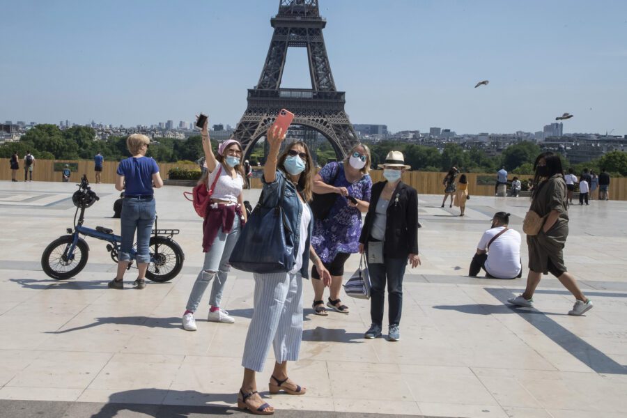 People wear face masks as they make a selfie at Trocadero square with the Eiffel Tower in Paris, Sunday, May 17, 2020 as France gradually lifts its Covid-19 lockdown. Parisians enjoying their first weekend in the sun since travel and movement restrictions were partially lifted. (AP Photo/Michel Euler)