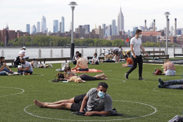 People relax in designated circles marked on the grass at Brooklyn’s Domino Park during the current coronavirus outbreak, Monday, May 18, 2020, in New York. The circles were added after the park became severely overcrowded duirng a spate of uneasonably warm weather just over a week ago. (AP Photo/Kathy Willens)