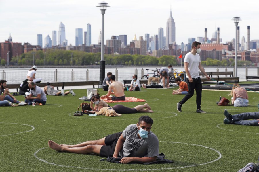 People relax in designated circles marked on the grass at Brooklyn’s Domino Park during the current coronavirus outbreak, Monday, May 18, 2020, in New York. The circles were added after the park became severely overcrowded duirng a spate of uneasonably warm weather just over a week ago. (AP Photo/Kathy Willens)