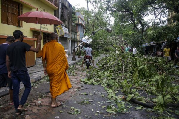 A Buddhist monk walks through a road laid with fallen trees and branches after Cyclone Amphan hit the region in Kolkata, India, Thursday, May 21, 2020. A powerful cyclone ripped through densely populated coastal India and Bangladesh, blowing off roofs and whipping up waves that swallowed embankments and bridges and left entire villages without access to fresh water, electricity and communications. (AP Photo/Bikas Das)