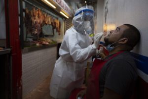 A medical worker from the Ministry of Health wearing a protective suit takes a sample to test for COVID-19 from a butcher at La Terminal market in Guatemala City, Thursday, May 21, 2020. (AP Photo/Moises Castillo)