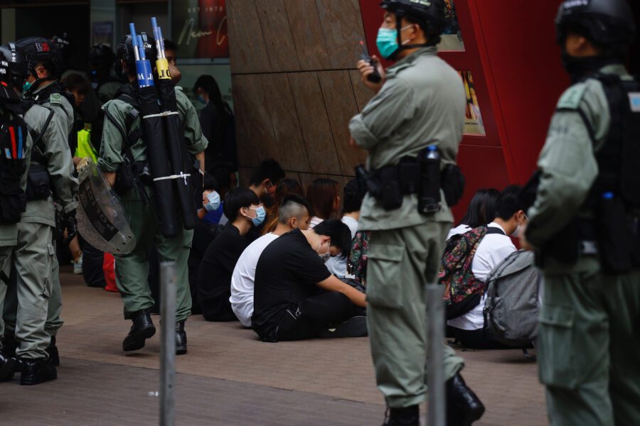 Riot police guard detained protesters in the Central district as a second reading of a controversial national anthem law takes place in Hong Kong, Wednesday, May 27, 2020. Hong Kong police massed outside the legislature complex Wednesday, ahead of debate on a bill that would criminalize abuse of the Chinese national anthem in the semi-autonomous city. (AP Photo/Kin Cheung)