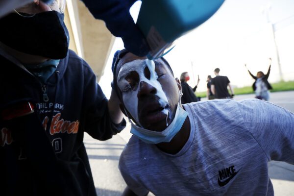 A protester is doused with milk Friday, May 29, 2020, in Minneapolis. Protests continued following the death of George Floyd, who died after being restrained by Minneapolis police officers on Memorial Day. (AP Photo/John Minchillo)