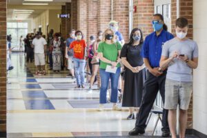 Voters wait in long lines at Peachcrest Elementary School to vote in the state’s primary election, Tuesday, June 9, 2020 in Decatur, Ga. Coronavirus restrictions only allow 10 people in the gym at a time so many machines are not being used, creating long wait times.(Jenni Girtman/Atlanta Journal-Constitution via AP)