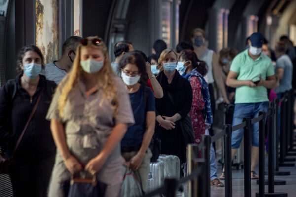 Passengers queue at a Corona test center at the airport in Frankfurt, Germany, Friday, Aug. 7, 2020. From Saturday on travelers coming back from one of the high-risk-countries have to do a Covid-19 test. (AP Photo/Michael Probst)
