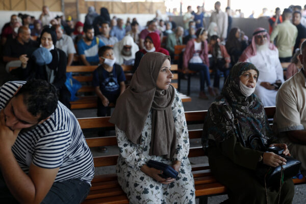 Passengers wait for passports to cross the border to the Egyptian side of Rafah crossing, in Rafah, Gaza Strip, Tuesday, Aug. 11, 2020. Egypt reopened Rafah Crossing for three days starting Tuesday for humanitarian cases in and out of the Gaza Strip, including medical patients and people who had Egyptian and international citizenship. The border was closed since March. (AP Photo/Adel Hana)