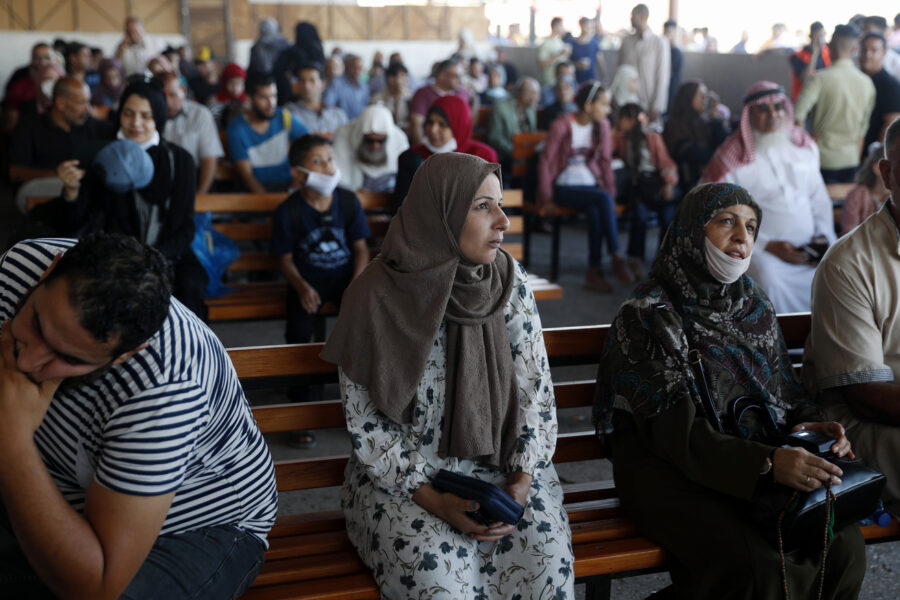Passengers wait for passports to cross the border to the Egyptian side of Rafah crossing, in Rafah, Gaza Strip, Tuesday, Aug. 11, 2020. Egypt reopened Rafah Crossing for three days starting Tuesday for humanitarian cases in and out of the Gaza Strip, including medical patients and people who had Egyptian and international citizenship. The border was closed since March. (AP Photo/Adel Hana)
