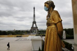 FILE- In this file photo dated Monday, May 4, 2020, a statue wears a mask along Trocadero square close to the Eiffel Tower in Paris. Britain will require all people arriving from France to isolate for 14 days – an announcement that throws the plans of tens of thousands of holiday makers into chaos. The government said late Thursday Aug. 13, 2020 that France is being removed from the list of nations exempted from quarantine requirements because of a rising number of coronavirus infections, which have surged by 66% in the past week.(AP Photo/Christophe Ena, File)
