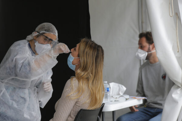 A medical technician administer a nasal swab to a woman at a mobile testing site outside the city hall in Paris, Monday, Aug. 31, 2020. With virus cases rising, France is struggling to administer enough tests to keep up with demands. (AP Photo/Michel Euler)