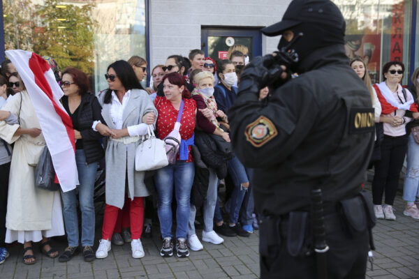 Women with old Belarusian national flags stand in front of a police officer during an opposition rally to protest the official presidential election results in Minsk, Belarus, Saturday, Sept. 19, 2020. Daily protests calling for the authoritarian president’s resignation are now in their second month and opposition determination appears strong despite the detention of protest leaders. (AP Photo/TUT.by)
