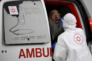 An Israeli medical worker wearing protective gear takes a swab from an ultra-Orthodox Jewish man for a coronavirus test, as part of the government’s measures to stop the spread of the virus, in the Orthodox city of Bnei Brak, a suburb of Tel Aviv, Israel, Tuesday, March 31, 2020. The new coronavirus causes mild or moderate symptoms for most people, but for some, especially older adults and people with existing health problems, it can cause more severe illness or death. (AP Photo/Ariel Schalit)