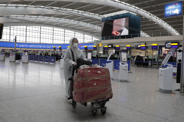 A traveller in protective clothing carries her luggage at Heathrow Airport in London, Wednesday, March 18, 2020. Britain’s Foreign Secretary Dominic Raab has taken the decision to advise British nationals against non-essential travel globally for an initial period of 30 days, and of course subject to ongoing review. For most people, the new coronavirus causes only mild or moderate symptoms, such as fever and cough. For some, especially older adults and people with existing health problems, it can cause more severe illness, including pneumonia.(AP Photo/Frank Augstein)