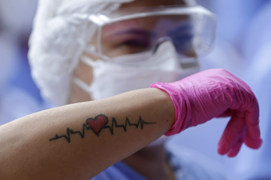 A medical worker shows her life sign tattoo while she and fellow workers celebrate as the last three patients are released from a field hospital at the National Stadium Mane Garrincha, after recuperating from COVID-19, in Brasilia, Brazil, Thursday, Oct. 15, 2020. (AP Photo/Eraldo Peres)