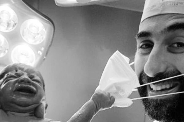 Il neonato che strappa la mascherina al medico, chi è il ginecologo della “foto della speranza”