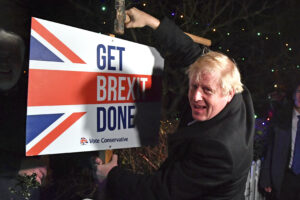 FILE — In this Wednesday, Dec. 11, 2019 file photo, Britain’s Prime Minister and Conservative party leader Boris Johnson poses as he hammers a "Get Brexit Done" sign into the garden of a supporter, in Benfleet, England. Britain and the European Union have struck a provisional free-trade agreement that should avert New Year chaos for cross-border traders and bring a measure of certainty for businesses after years of Brexit turmoil.  (Ben Stansall/Pool via AP, File)