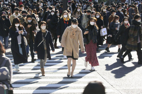 People wearing face masks to help curb the spread of the coronavirus walk around the scrambled intersection at the Shibuya shopping district in Tokyo Saturday, Dec. 26, 2020. Tokyo has confirmed 949 new cases of the coronavirus on Saturday, a record high for the Japanese capital, as the country struggles with an upsurge that is spreading nationwide. (Kyodo News via AP)