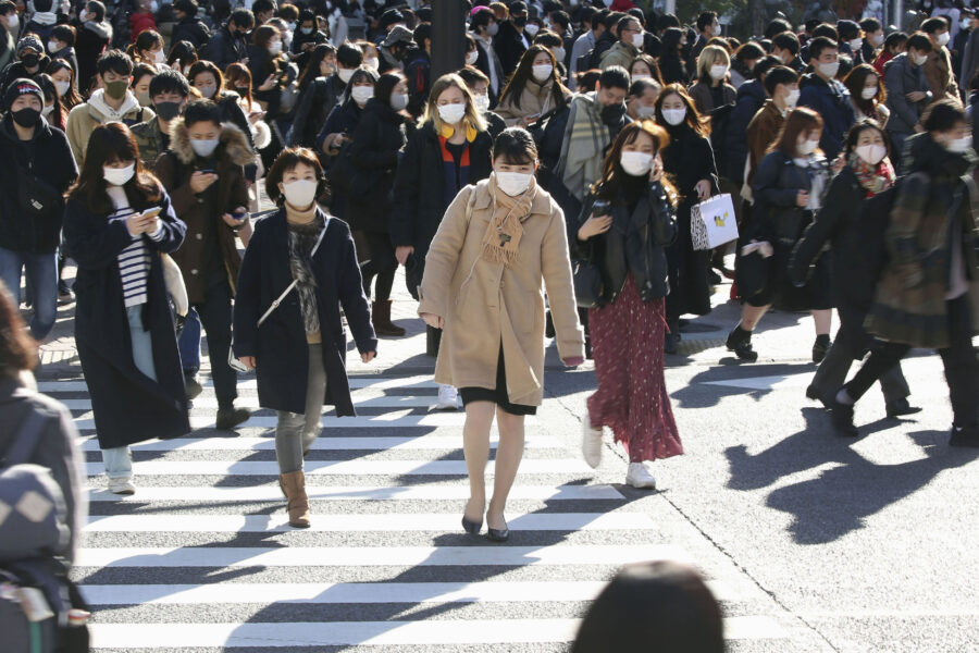 People wearing face masks to help curb the spread of the coronavirus walk around the scrambled intersection at the Shibuya shopping district in Tokyo Saturday, Dec. 26, 2020. Tokyo has confirmed 949 new cases of the coronavirus on Saturday, a record high for the Japanese capital, as the country struggles with an upsurge that is spreading nationwide. (Kyodo News via AP)