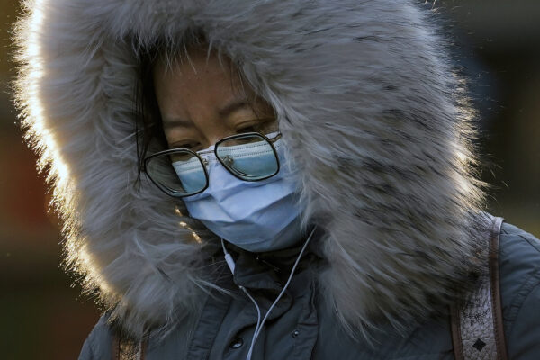 A woman wearing a face mask to help curb the spread of the coronavirus walks on a street in Beijing, Monday, Jan. 4, 2021. Wary of another wave of infections, China is urging tens of millions of migrant workers to stay put during next month’s Lunar New Year holiday, usually the world’s largest annual human migration. (AP Photo/Andy Wong)
