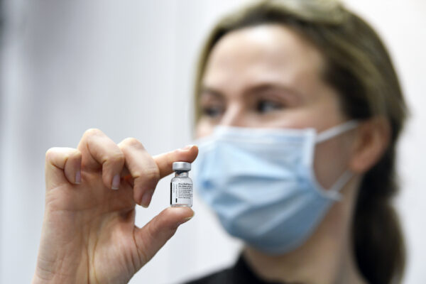 A woman holds the empty container of the first used Pfizer/BioNTech coronavirus vaccine used in The Netherlands at a mass vaccination center in Veghel, Wednesday Jan. 6, 2021. Nearly two weeks after most other European Union nations, the Netherlands on Wednesday began its COVID-19 vaccination program, with care home staff and frontline workers in hospitals first in line for the shot. (Piroschka van de Wouw/Pool via AP)