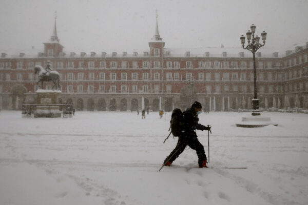 A man skis while crossing the Plaza Mayor during a heavy snowfall in Madrid, Spain, Saturday, Jan. 9, 2021. An unusual and persistent blizzard has blanketed large parts of Spain with snow, freezing traffic and leaving thousands trapped in cars or in train stations and airports that had suspended all services as the snow kept falling on Saturday. The capital, Madrid, and other parts of central Spain activated for the first time its red weather alert, its highest, and called in the military to rescue people from cars vehicles trapped in everything from small roads to the city’s major thoroughfares. (AP Photo/Andrea Comas)