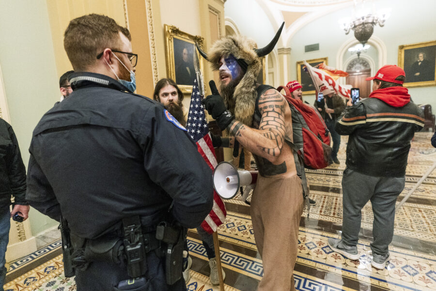 FILE – In this Jan. 6, 2021, file photo supporters of President Donald Trump are confronted by U.S. Capitol Police officers outside the Senate Chamber inside the Capitol in Washington. An Arizona man seen in photos and video of the mob wearing a fur hat with horns was also charged Saturday in Wednesday’s chaos. Jacob Anthony Chansley, who also goes by the name Jake Angeli, was taken into custody Saturday, Jan. 9. (AP Photo/Manuel Balce Ceneta, File)