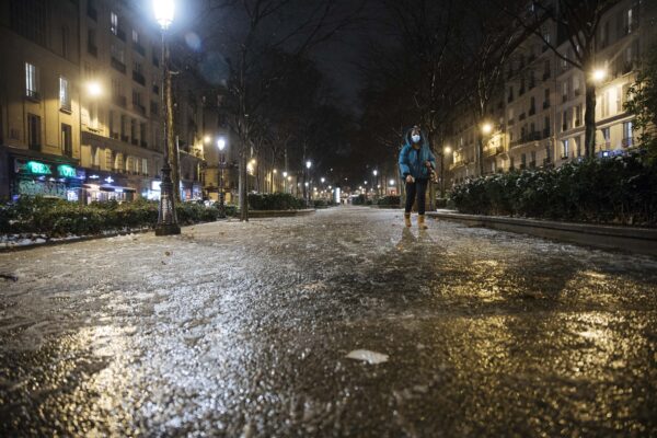 A woman walks in an empty street as the 6 p.m curfew starts in Paris, Saturday Jan.16, 2021. The prime minister announced Thursday an extension of the 6 p.m.-to-6 a.m. curfew to cover the whole country, including zones, like Paris, where it previously hadn’t started until 8 p.m. Shopping and all outdoor leisure activities stop at curfew, only short pet walks allowed. Working and commuting allowed with note from employer. Food deliveries but not takeout allowed. Fines for curfew-breakers. (AP Photo/Lewis Joly)