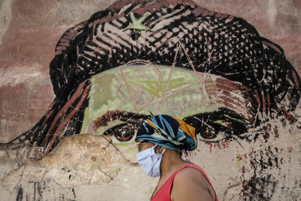 A woman wearing a protective face mask amid the new coronavirus pandemic, walks past a dilapidated mural featuring Argentine-born Cuban revolutionary hero Ernesto “Che” Guevara, in Old Havana, Cuba, Tuesday, Jan. 19, 2021. ( AP Photo/Ramon Espinosa)
