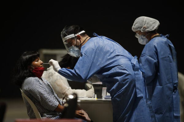 A healthcare worker tests a school staffer for COVID-19 in Buenos Aires, Argentina, Tuesday, Feb. 9, 2021. The capital city is preparing for the return of the in-person class on Feb. 17. (AP Photo/Natacha Pisarenko)