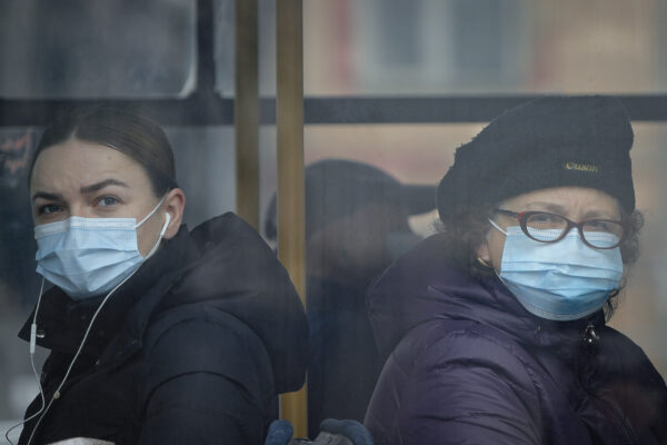 People watch protesting policemen from a passing bus in Bucharest, Romania, Wednesday, Feb. 24, 2021. Hundreds of Romanian policemen gathered outside the Cotroceni Presidential Palace in protest of planned austerity measures that envisage freezing of salaries in the public sector. (AP Photo/Vadim Ghirda)