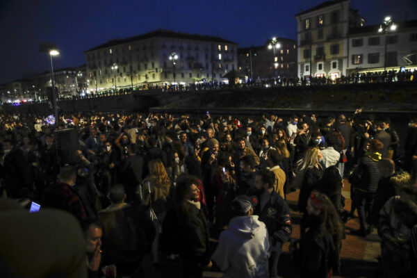 People gather at the Darsena dei Navigli, in Milan, Italy, Saturday, Feb. 27, 2021. Police vans blocked entrance to Milan’s trendy Navigli neighborhood Saturday evening after the mayor announced increased patrols to prevent gatherings during a spring-like weekend. The Lombardy region where Milan is located is heading toward a partial lockdown on Monday, and Mayor Giuseppe Sala said in a video message that he was disturbed by scenes of people gathering in public places, often with their masks down. (AP Photo/Luca Bruno)