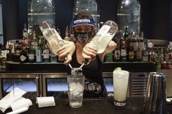 A bartender mixes a drink while wearing a mask and face shield at Slater’s 50/50 Wednesday, July 1, 2020, in Santa Clarita, Calif. California Gov. Gavin Newsom has ordered a three-week closure of bars, indoor dining and indoor operations of several other types of businesses in various counties, including Los Angeles, as the state deals with increasing coronavirus cases and hospitalizations. (AP Photo/Marcio Jose Sanchez)