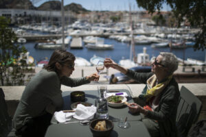 Charlotte Barrau and her mother Dany Barrau share a toast on a restaurant terrace, in La Ciotat southern France, Wednesday, May 19, 2021. Cafe and restaurant terraces reopened Wednesday after a pandemic shutdown of more than six months deprived people of what feels like the essence of life in France. The French government is lifting restrictions incrementally to stave off a resurgence of COVID-19 and to give citizens back some of their signature “joie de vivre.”(AP Photo/Daniel Cole)