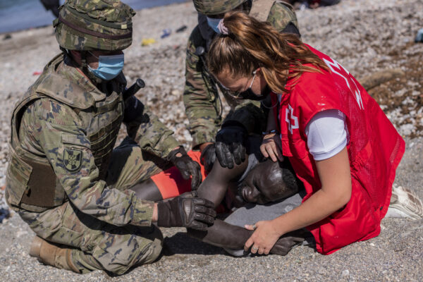 A migrant is comforted by a member of the Spanish Red Cross near the border of Morocco and Spain, at the Spanish enclave of Ceuta, on Tuesday, May 18, 2021. Spain has sent its military to the Moroccan border as thousands of migrants walked or swam into Europe for the second day in a row after Rabat loosened border controls in a diplomatic spat. (AP Photo/Bernat Armangue)
