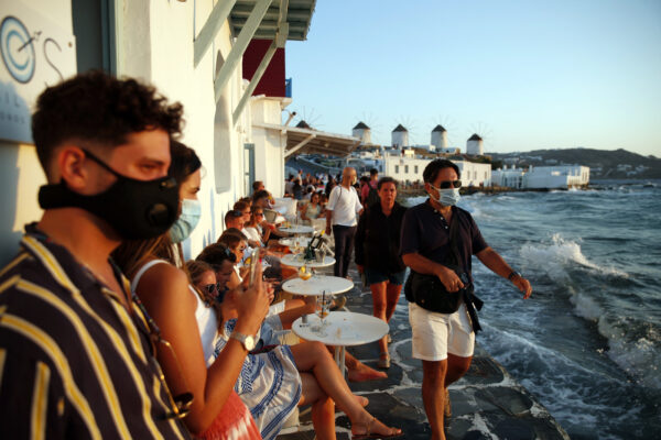 People, some of them wearing face masks against the spread of the new coronavirus, gather in Little Venice on the Aegean Sea island of Mykonos, Greece, Sunday, Aug. 16, 2020. Wary of a rise in daily coronavirus cases that threatens to undo its relative success in containing the pandemic so far, the Greek government is imposing local restrictions on businesses, especially those that cater to big crowds, and business owners on the island of Mykonos don’t like it one bit. (AP Photo/Thanassis Stavrakis)