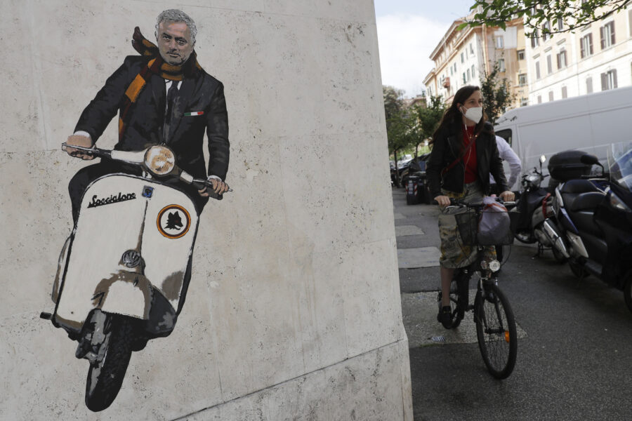 A woman rides her bicycle near a mural depicting coach Jose’ Mourinho riding a Vespa scooter adorned with the Roma soccer team symbol and wearing a red and yellow scarf in the Testaccio neighborhood of Rome, Friday, May 7, 2021. Mourinho, that most outspoken of soccer coaches, will take over next season at Roma, the team with some of the most outspoken fans in Italy. Having memorably declared himself the “Special One” when he first reached the big time at Chelsea in 2004, one of Mourinho’s most famous phrases in Italy was uttered at the expense of Roma five years later. (AP Photo/Gregorio Borgia)