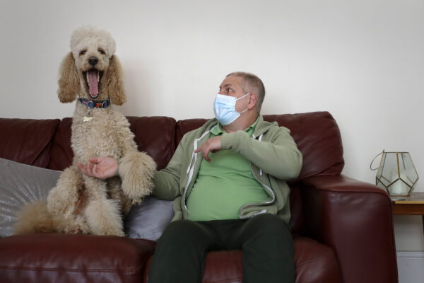 Long COVID patient Gary Miller sits on his sofa at home with his dog Rupert in London, Tuesday, May 11, 2021. For taxi driver Miller, recovery is agonizingly slow. He says there are times “I feel like I’m taking one step forward, and then all of a sudden — bang — I’m ill again and I take two steps back.” (AP Photo/Kirsty Wigglesworth)