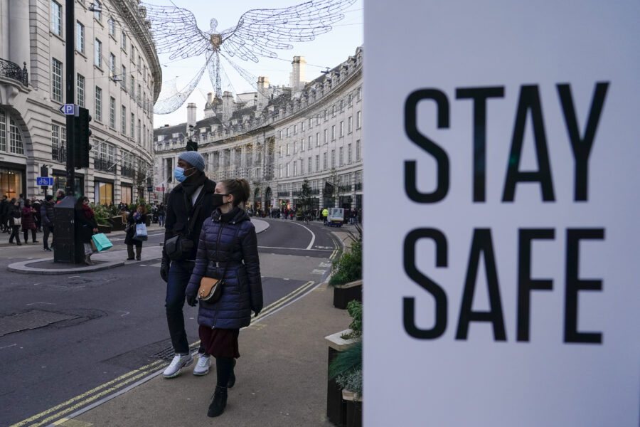 People wear face masks as they walk, in Regent Street, in London, Sunday, Nov. 28, 2021. Britain’s Prime Minister Boris Johnson said it was necessary to take “targeted and precautionary measures” after two people tested positive for the new variant in England. He also said mask-wearing in shops and on public transport will be required. (AP Photo/Alberto Pezzali)
