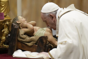 Pope Francis kisses a statue of Baby Jesus as he celebrates Christmas Eve Mass, at St. Peter’s Basilica, at the Vatican, Friday Dec. 24, 2021. (AP Photo/Alessandra Tarantino)