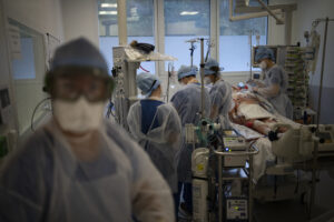 Medical workers tend to a patient suffering with COVID-19 and on a ventilator in the intensive care unit at the la Timone hospital in Marseille, southern France, Thursday, Dec. 23, 2021. (AP Photo/Daniel Cole)